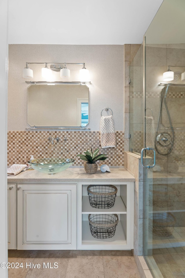 bathroom featuring decorative backsplash, an enclosed shower, and sink