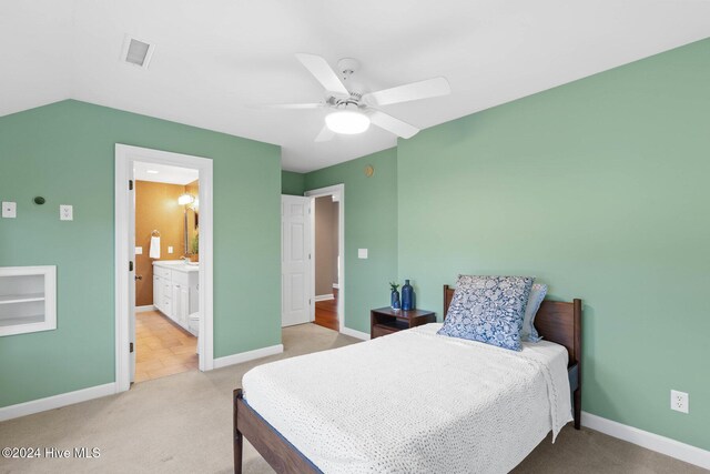 bedroom with ceiling fan, light carpet, and connected bathroom