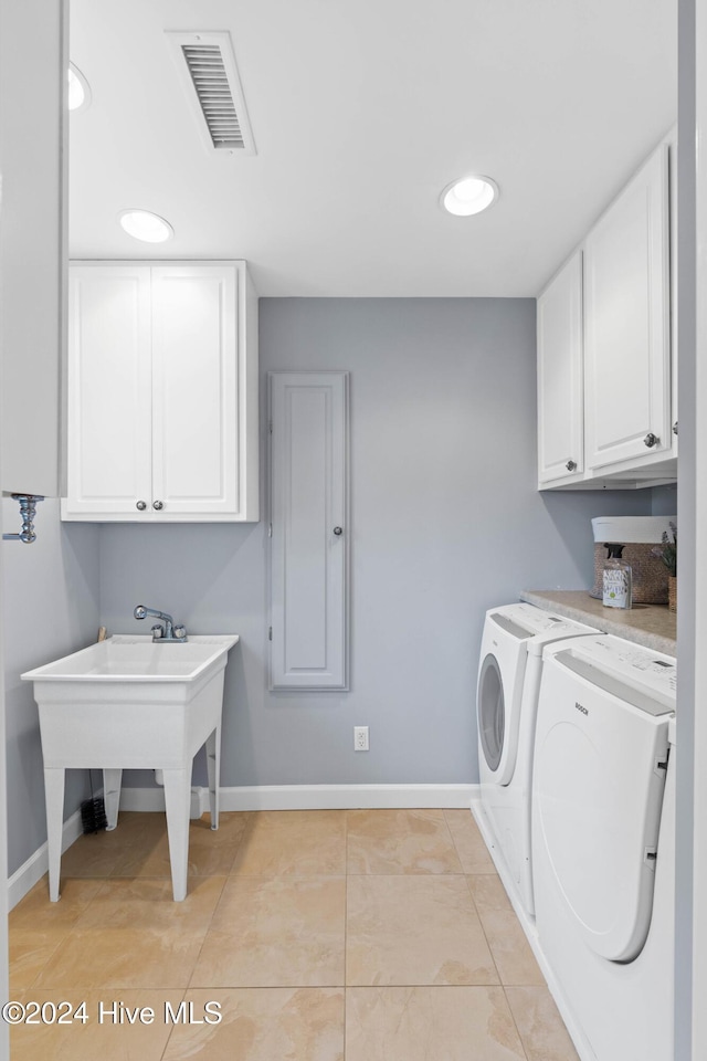 clothes washing area with cabinets, independent washer and dryer, and light tile patterned floors