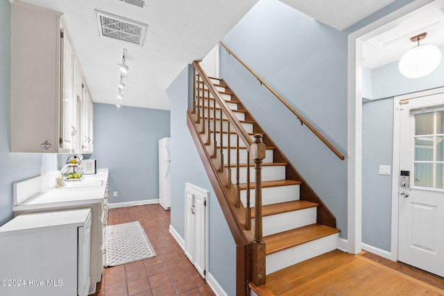 stairs with wood-type flooring and track lighting