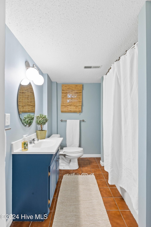 bathroom with tile patterned flooring, vanity, a textured ceiling, and toilet