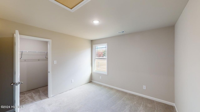 unfurnished bedroom featuring light colored carpet, a spacious closet, and a closet