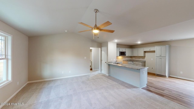 kitchen featuring a healthy amount of sunlight, kitchen peninsula, white cabinetry, and vaulted ceiling