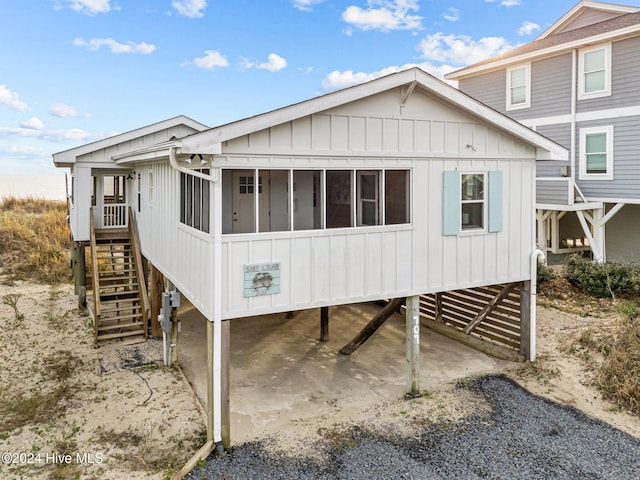 rear view of house featuring a sunroom and a carport