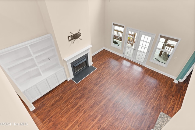 unfurnished living room featuring french doors, a towering ceiling, and dark hardwood / wood-style floors