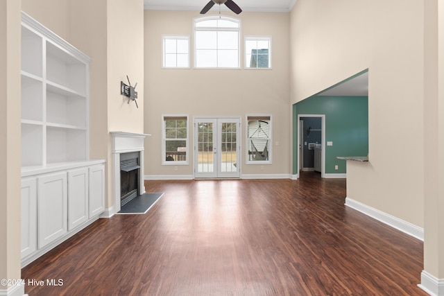 unfurnished living room featuring ceiling fan, french doors, a high ceiling, dark hardwood / wood-style flooring, and beamed ceiling