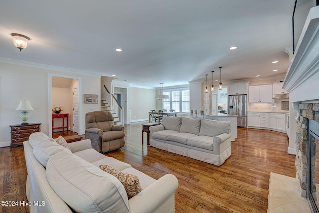 living room featuring a fireplace, wood-type flooring, and crown molding