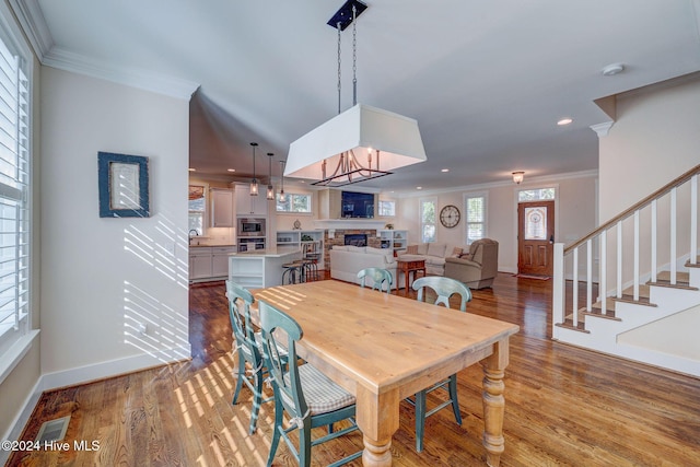 dining space featuring crown molding, sink, and hardwood / wood-style flooring