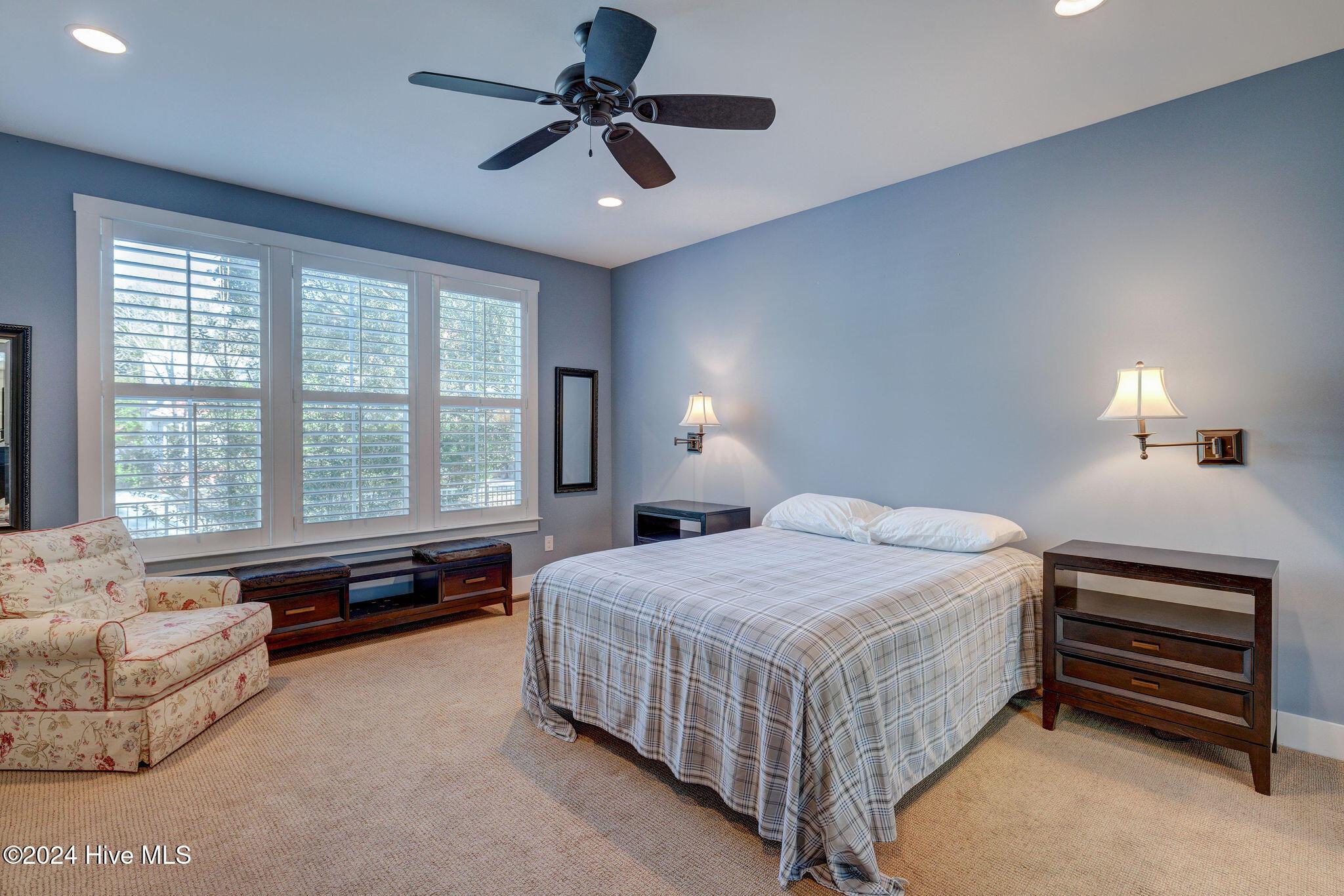 carpeted bedroom with multiple windows and ceiling fan