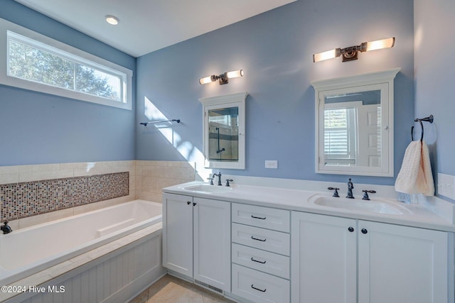 bathroom featuring tile patterned flooring, vanity, a healthy amount of sunlight, and a washtub