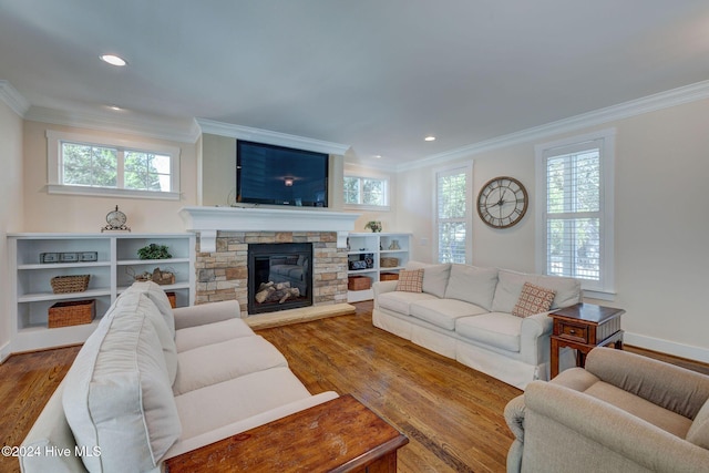 living room featuring a stone fireplace, wood-type flooring, and crown molding