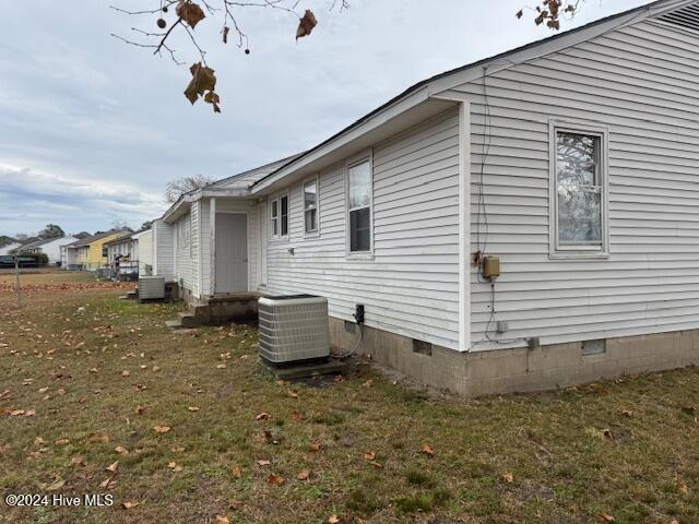 view of side of home with a lawn and central AC unit