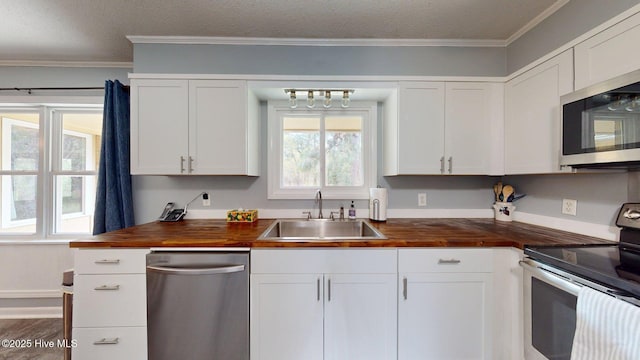 kitchen with a sink, appliances with stainless steel finishes, crown molding, and wooden counters