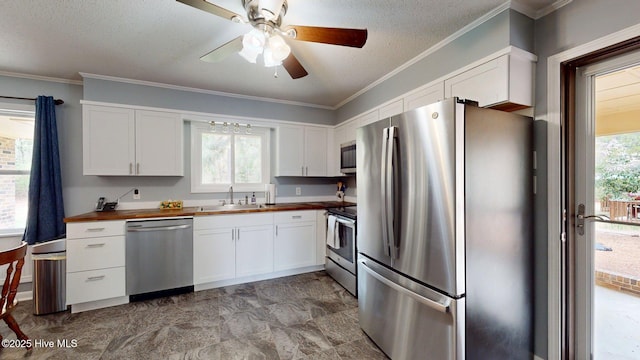 kitchen featuring appliances with stainless steel finishes, butcher block counters, white cabinets, ceiling fan, and a sink