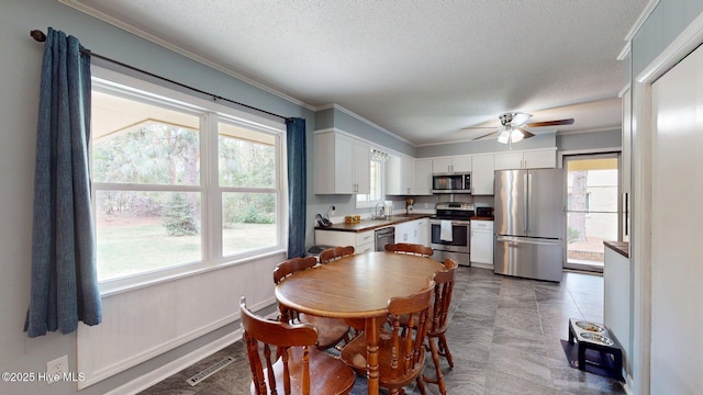 dining area with ceiling fan, ornamental molding, visible vents, and a wealth of natural light