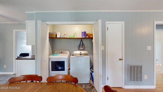 washroom with laundry area, washing machine and dryer, ornamental molding, and visible vents