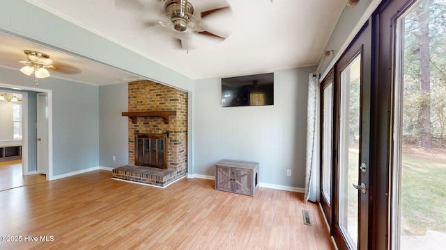 unfurnished living room with a wealth of natural light, light wood-style flooring, visible vents, and a ceiling fan