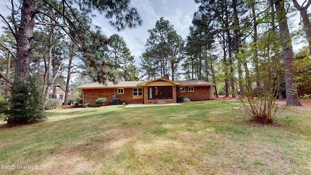 back of property featuring a chimney, a yard, and brick siding