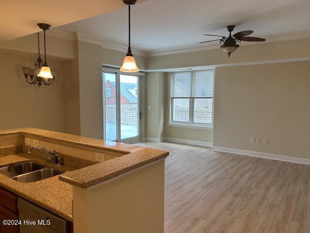 kitchen featuring ornamental molding, open floor plan, a sink, and hanging light fixtures