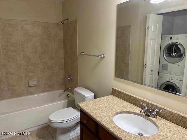 bathroom with stacked washer and clothes dryer, toilet, tile patterned floors, bathtub / shower combination, and vanity