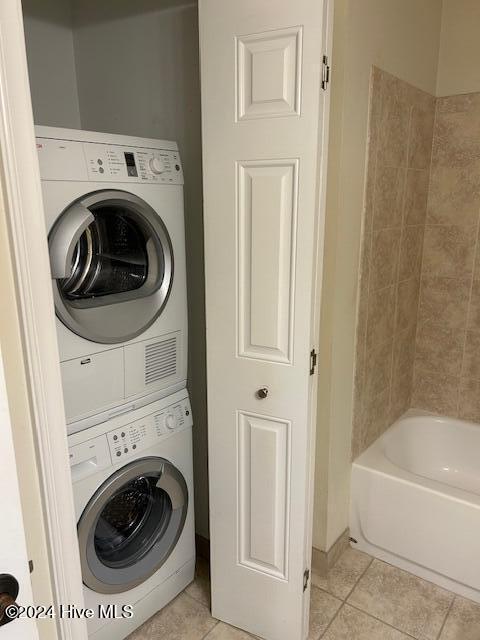 laundry area featuring light tile patterned floors, laundry area, and stacked washer / dryer