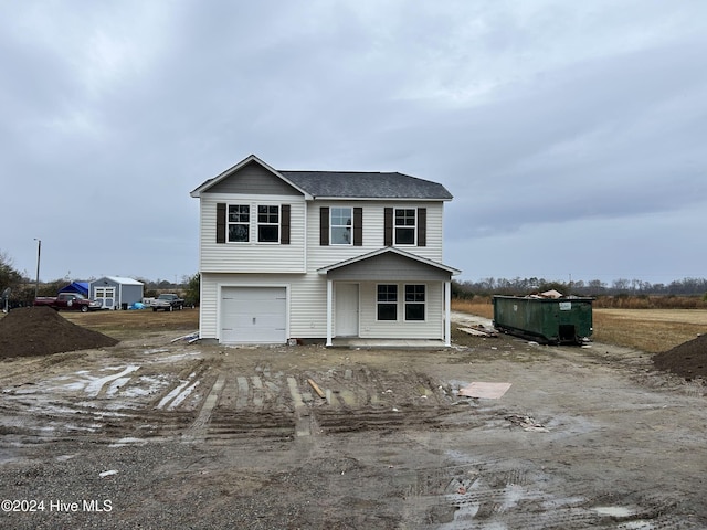 view of front of home with dirt driveway and an attached garage