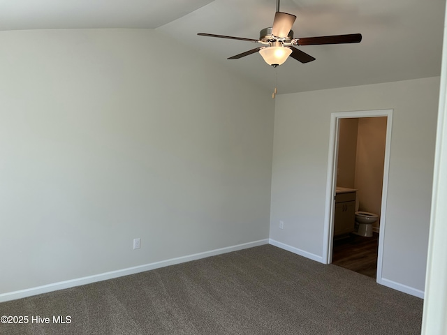 empty room featuring a ceiling fan, vaulted ceiling, dark carpet, and baseboards