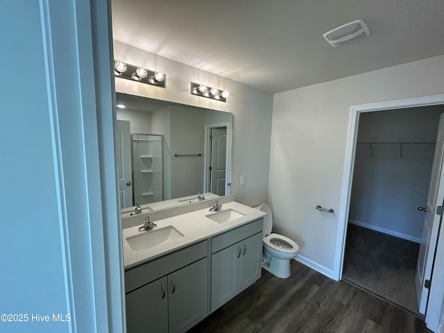 bathroom with double vanity, visible vents, a sink, and wood finished floors