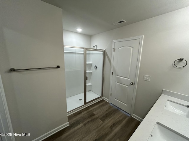 full bath with double vanity, visible vents, a stall shower, wood finished floors, and baseboards