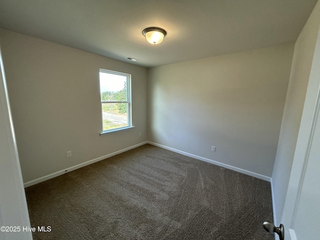 empty room featuring visible vents, baseboards, and dark colored carpet