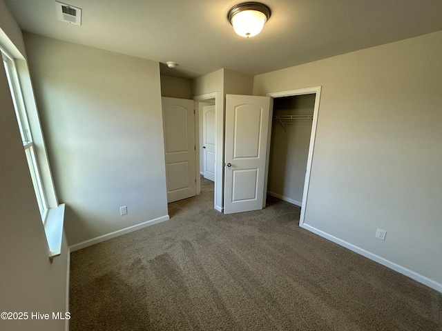 unfurnished bedroom with carpet floors, a closet, visible vents, and baseboards