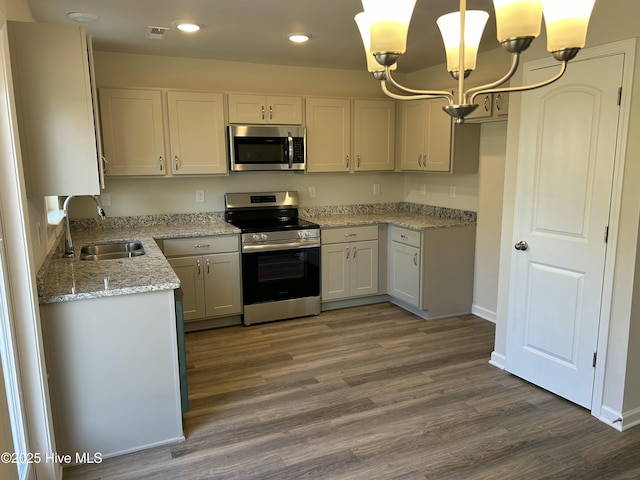 kitchen featuring stainless steel appliances, a sink, visible vents, white cabinets, and hanging light fixtures