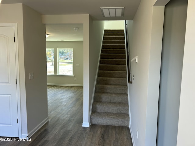 stairway with baseboards, visible vents, and wood finished floors