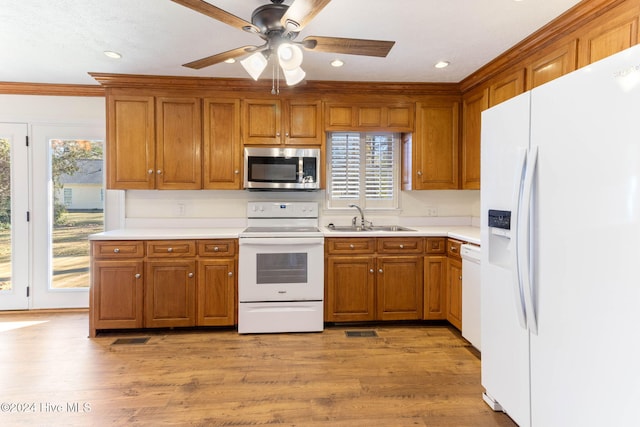 kitchen with light hardwood / wood-style flooring, ornamental molding, white appliances, and sink