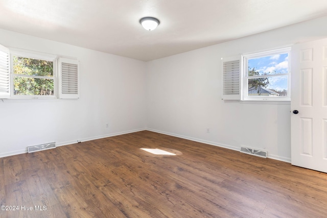 spare room featuring dark hardwood / wood-style floors and a healthy amount of sunlight