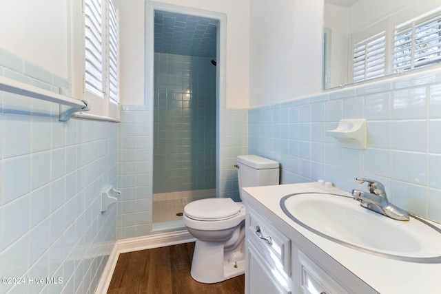 bathroom with hardwood / wood-style flooring, toilet, walk in shower, and tile walls