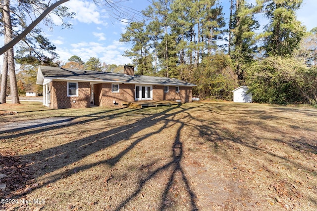 rear view of property with a storage shed and a lawn