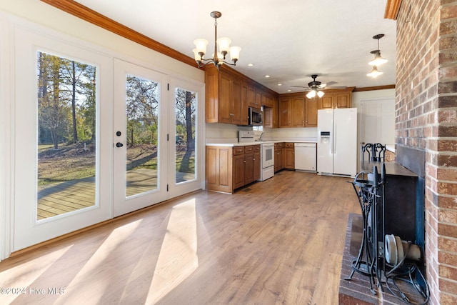 kitchen with hanging light fixtures, crown molding, light hardwood / wood-style floors, white appliances, and ceiling fan with notable chandelier