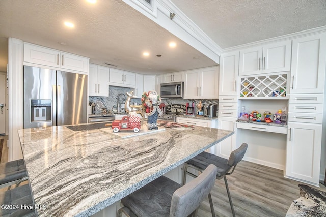 kitchen featuring light stone countertops, white cabinetry, and appliances with stainless steel finishes