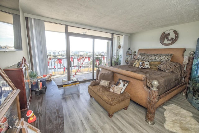 bedroom with floor to ceiling windows, a textured ceiling, access to outside, and multiple windows