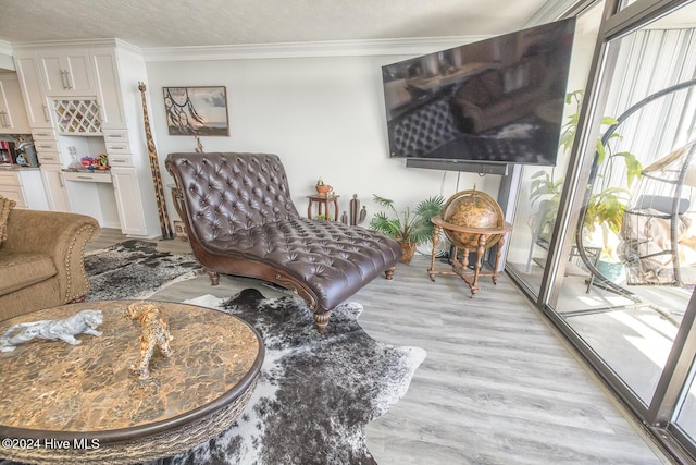 sitting room with a textured ceiling, light hardwood / wood-style flooring, and ornamental molding