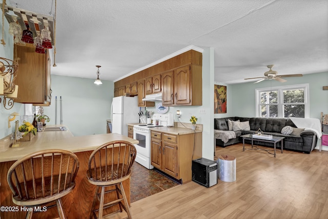 kitchen with kitchen peninsula, ceiling fan, white appliances, a textured ceiling, and sink