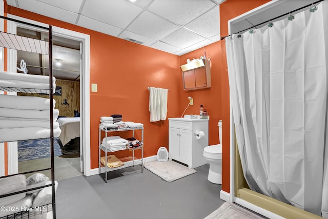 bathroom featuring toilet, a paneled ceiling, concrete flooring, and vanity