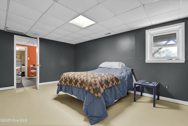 bedroom featuring a drop ceiling and concrete floors