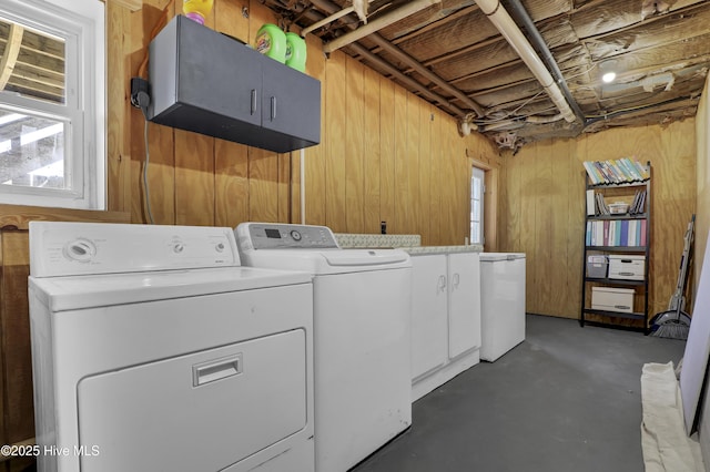 laundry room featuring cabinets, washer and clothes dryer, a healthy amount of sunlight, and wooden walls