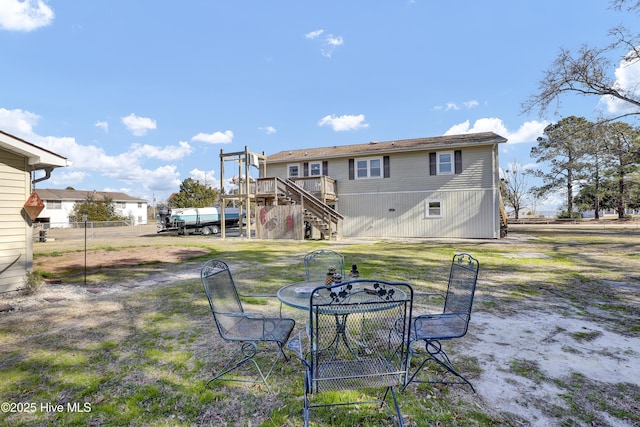 rear view of property with a lawn, fence, stairway, and a deck