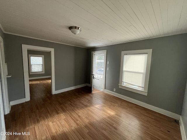 spare room featuring wooden ceiling, dark wood-type flooring, crown molding, and a healthy amount of sunlight