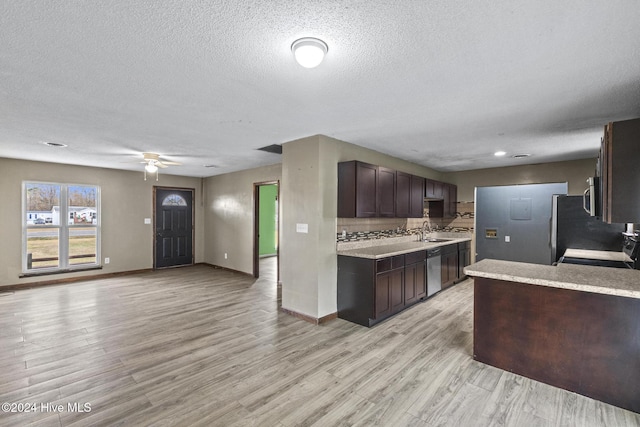 kitchen featuring dark brown cabinets, a textured ceiling, stainless steel appliances, sink, and light hardwood / wood-style floors