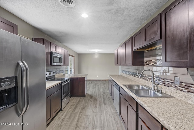 kitchen featuring decorative backsplash, dark brown cabinets, stainless steel appliances, sink, and light hardwood / wood-style floors