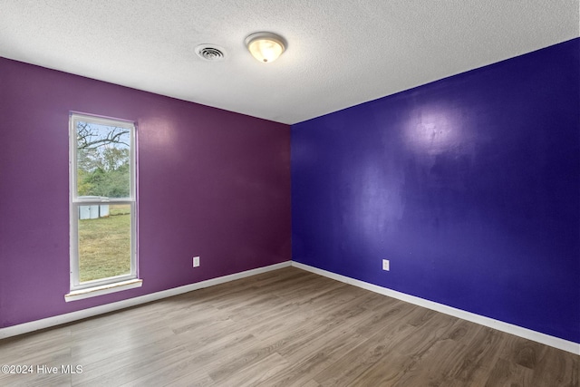 unfurnished room featuring hardwood / wood-style floors and a textured ceiling